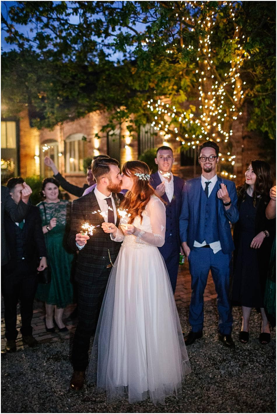 Bride and Groom holding sparklers and kissing at Curradine Barns