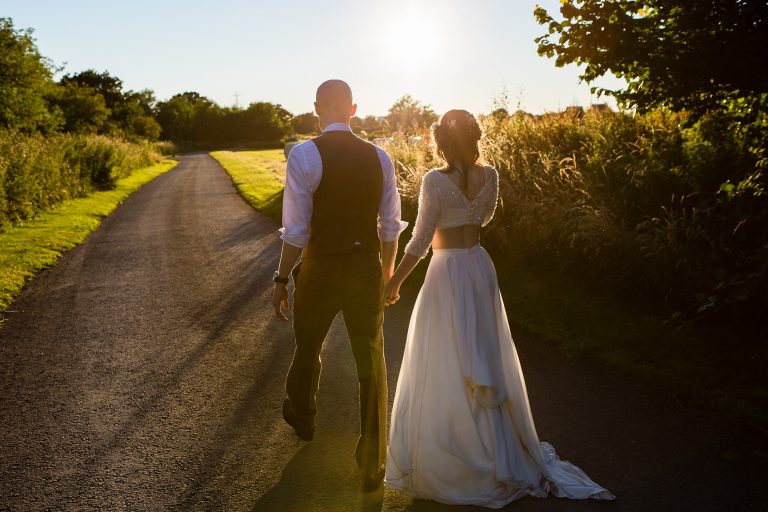 Shustoke Barn wedding photography; Couple holding hands walking