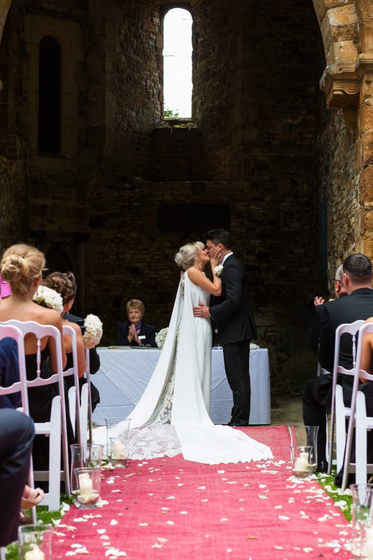 Ettington Park Hotel Wedding Photography; Bride & Groom kiss during outdoor ceremony