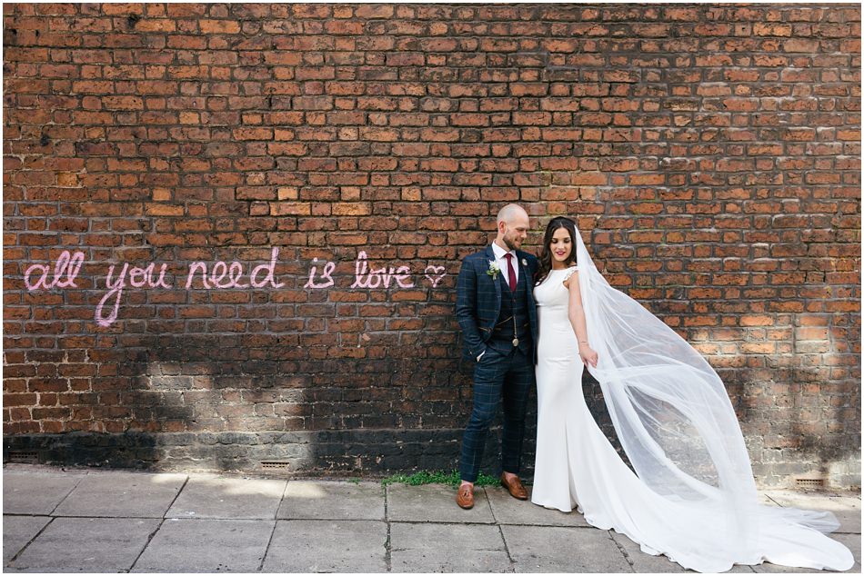 Hope Street Hotel wedding photography; Bride & Groom stand in front of Beatles lyrics wall