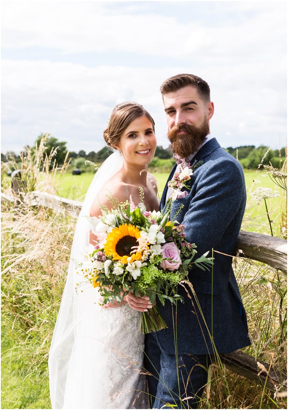 Groom with beard and wearing a dickie bow and Bride with rustic bouquet with sunflowers at Shustoke Barn 