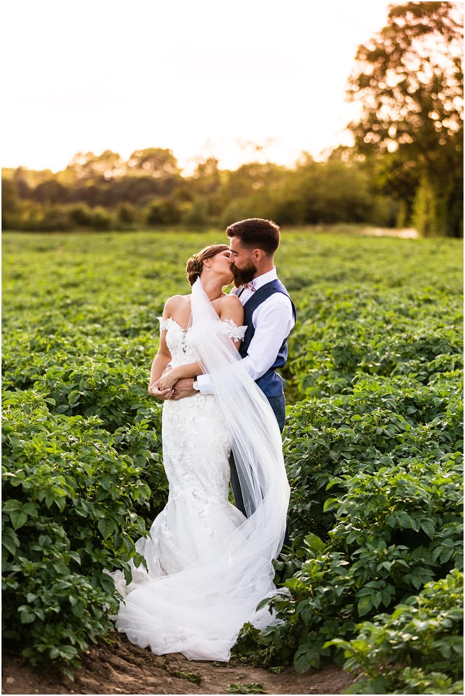 Shustoke Barn wedding; bride and groom kissing at sunset