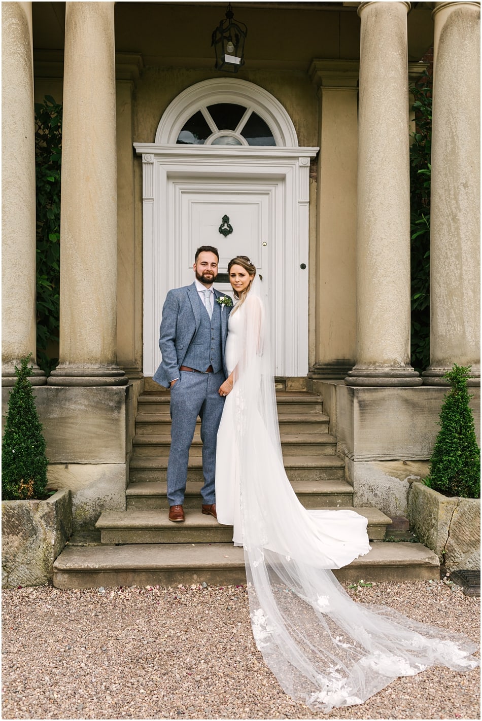 Couple pose on the front steps of Iscoyd Park on their wedding day