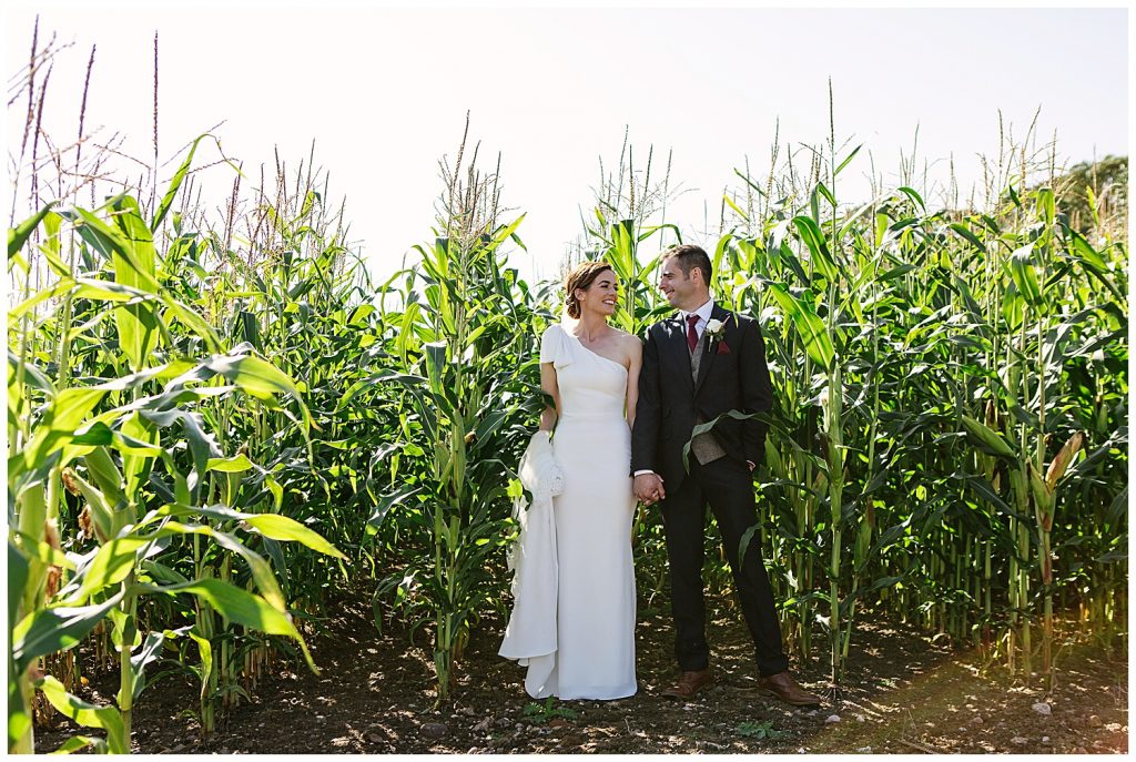 Bride and Groom stand in cob field for wedding portrait
