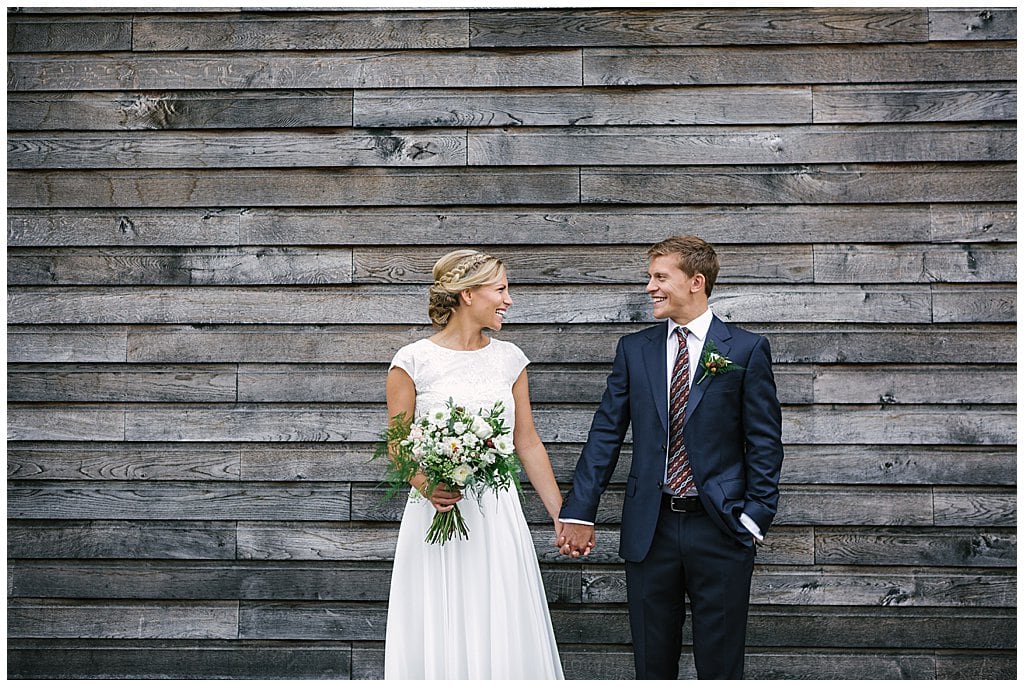 Fun, natural portrait of Bride and Groom holding hands in front of a wedding barn