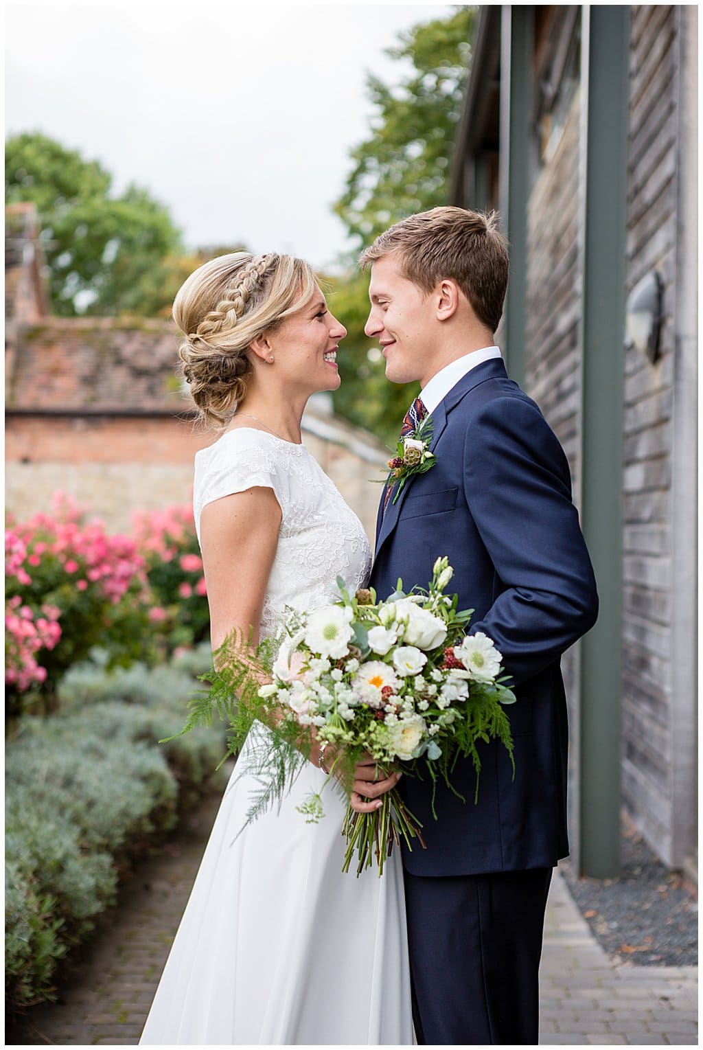 Newly married couple pose with Brides flowers outside their country barn venue