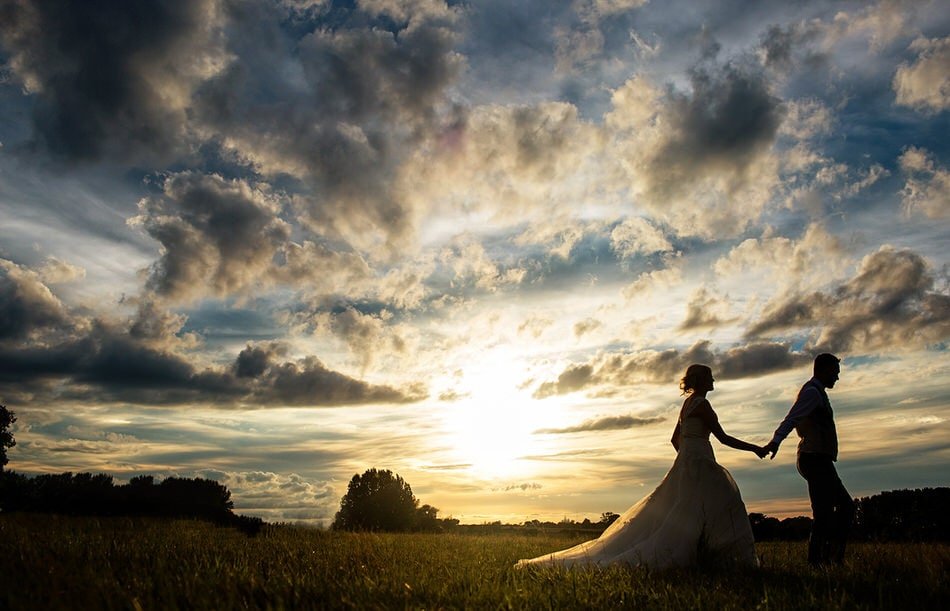 Bride and Groom walking against an epic sky 