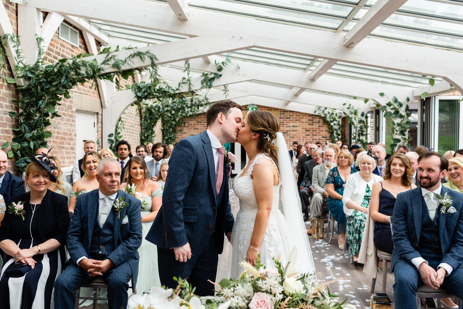 Newly married Bride & Groom kiss during their wedding ceremony at Foxtail Barns