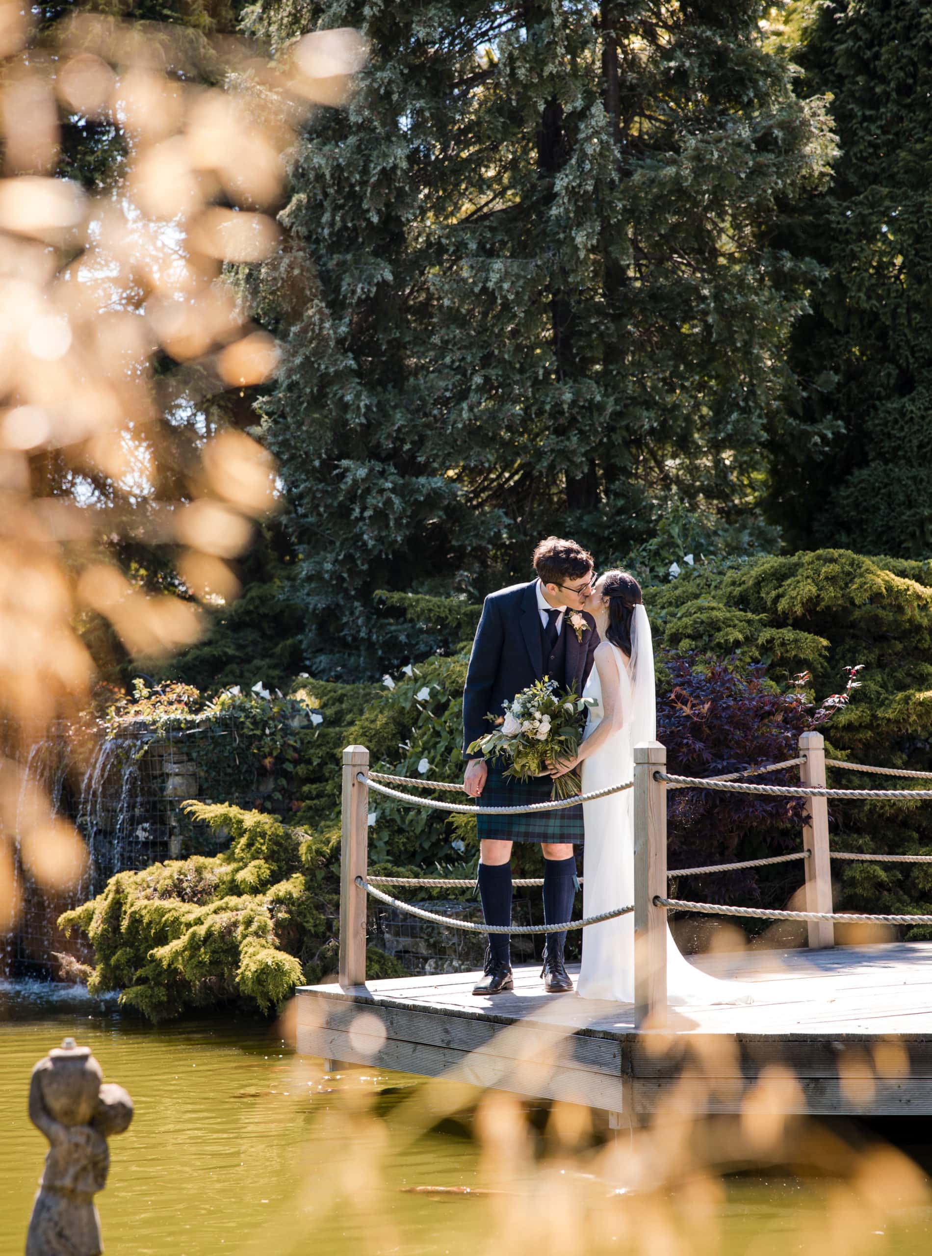 newly married couple kissing on jetty over a lake at best wedding barn venue in West Midlands
