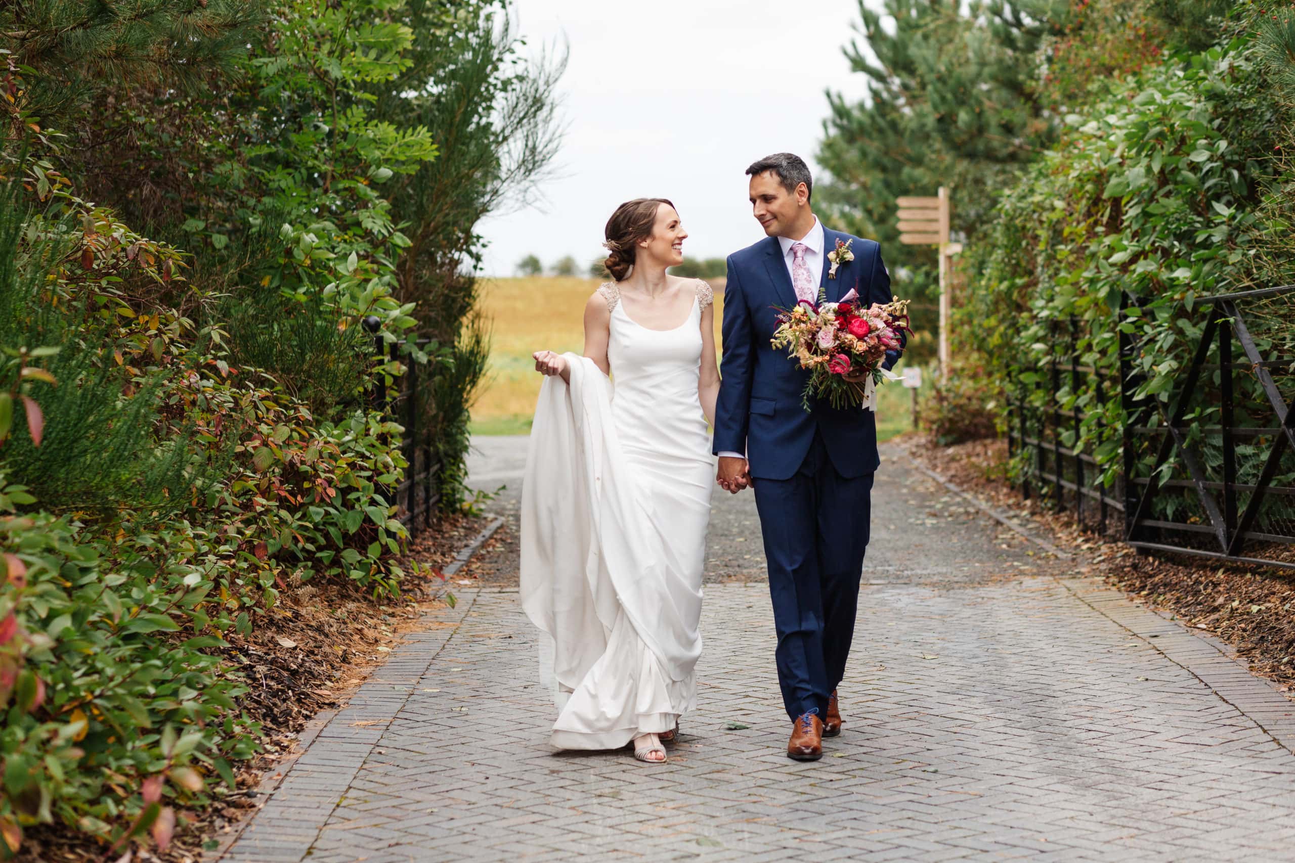Candid moment between bride and groom holding hands and walking at Swallows Nest Barn