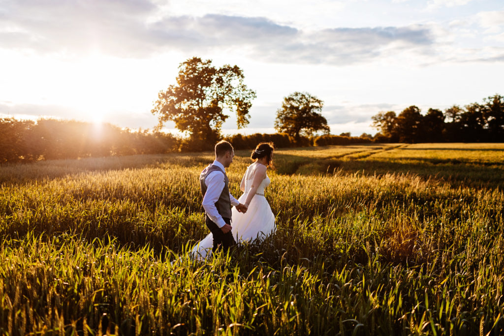wedding photographer Alrewas Hayes; Couple holding hands walking at sunset