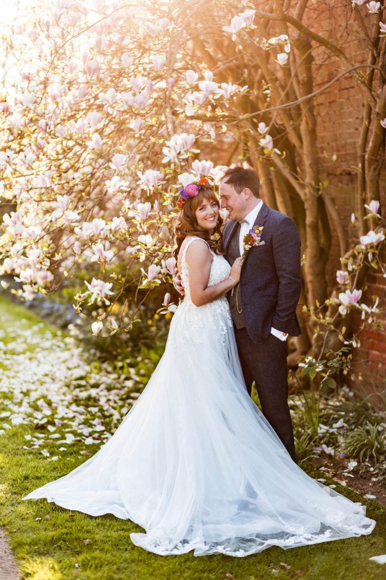 Golden hour portrait of Bride and Groom standing in front of a Magnolia tree at Thorpe Garden