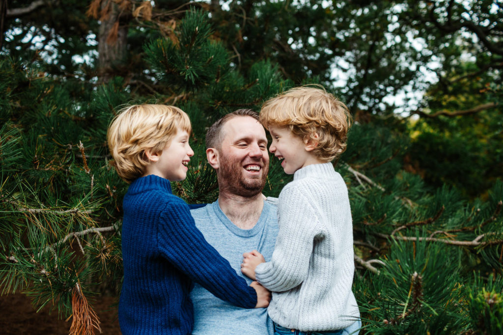 natural family photoshoot; Dad picking up his two young sons laughing