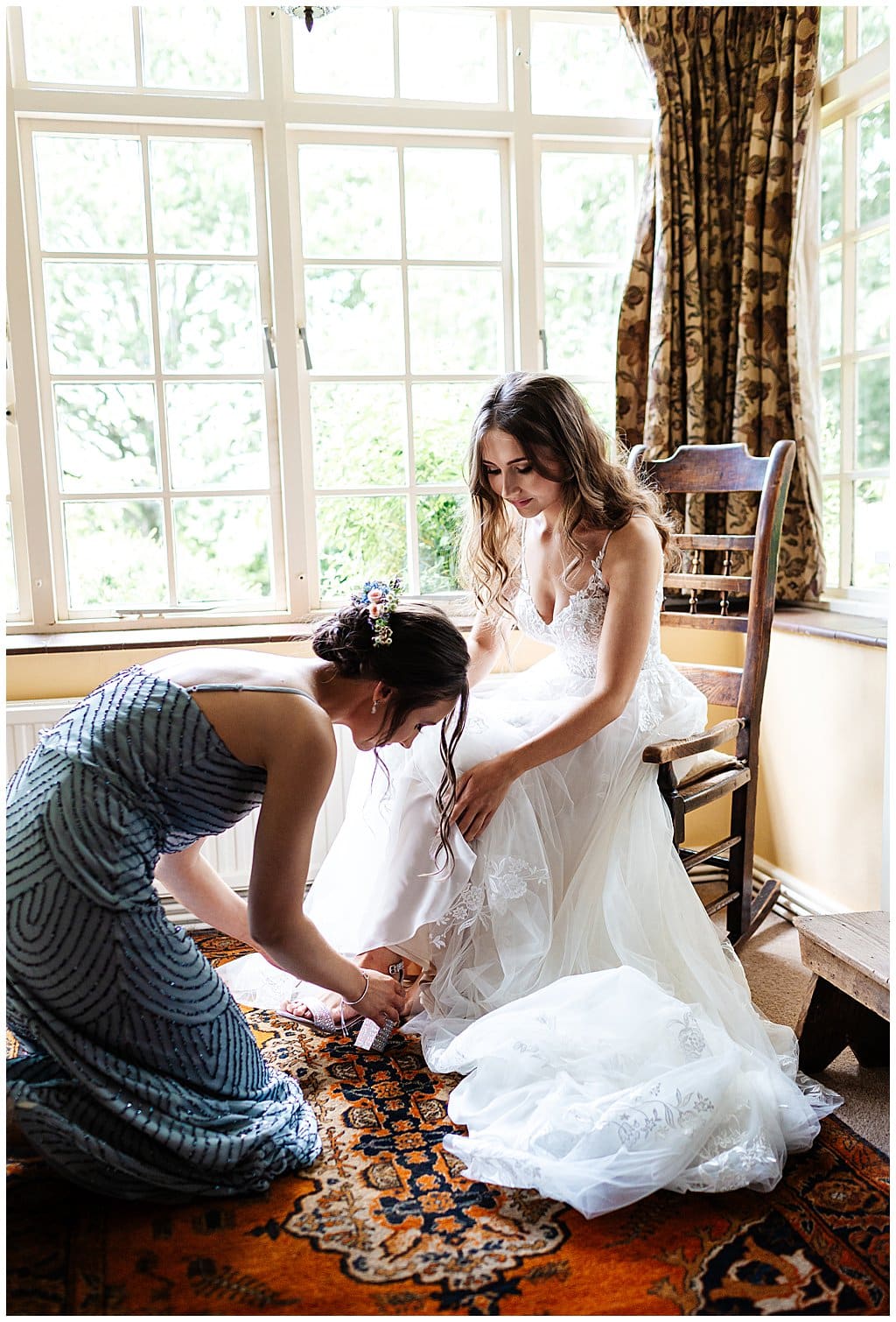 bridesmaids in beaded grey dress, helps bride wearing strappy Pronovias dress, put on shoes