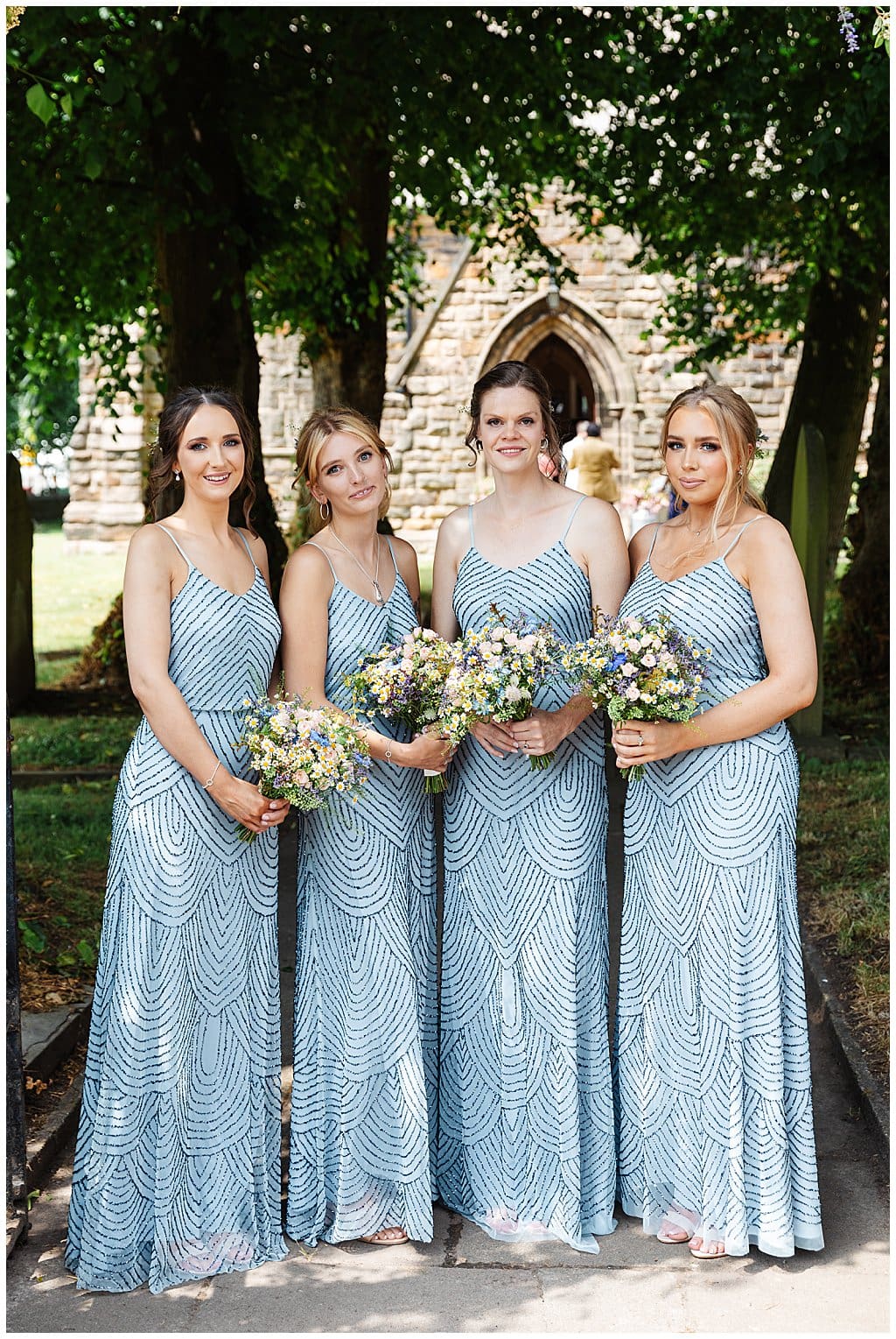 Bridesmaids in silver beaded scrappy dresses outside Smallwood Church