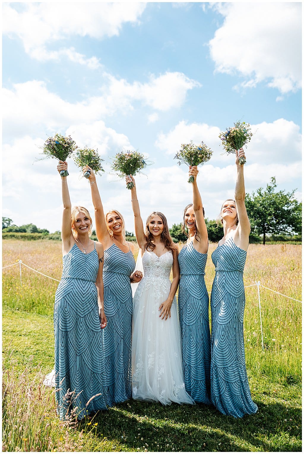 bride with bridesmaids raising bouquets in the air