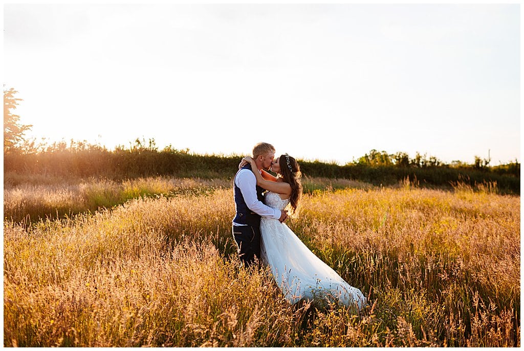 Bride and Groom kiss in field of long grass at golden hour in Smallwood