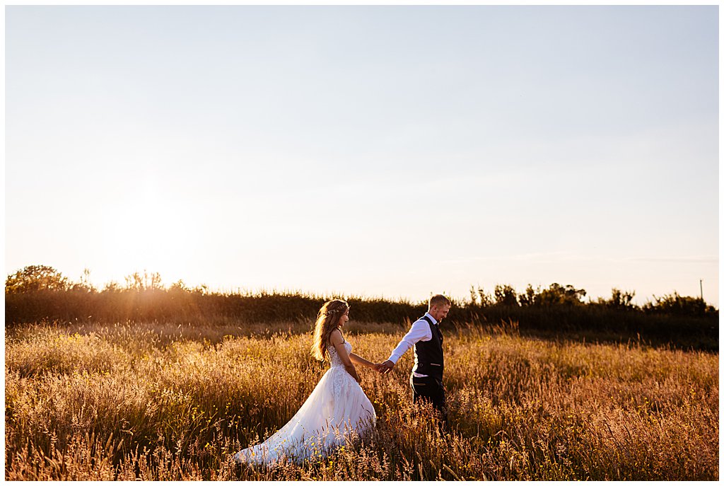 Smallwood wedding photography; couple walking through fields, holding hands, at sunset
