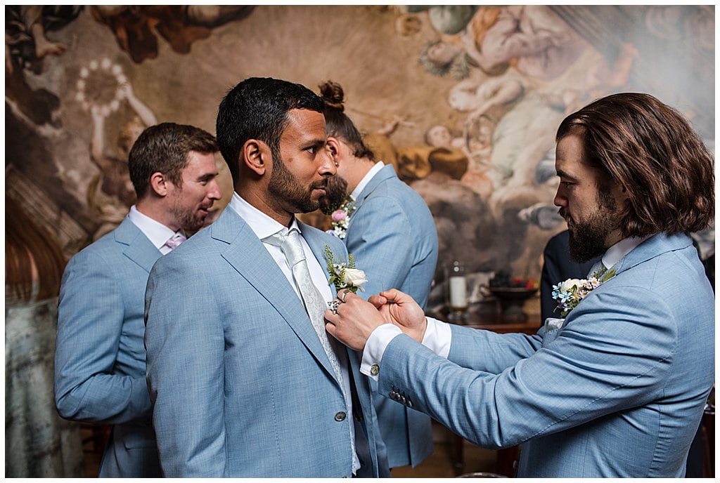 Groomsmen pinning button holes in front of Alrewas Hayes mural