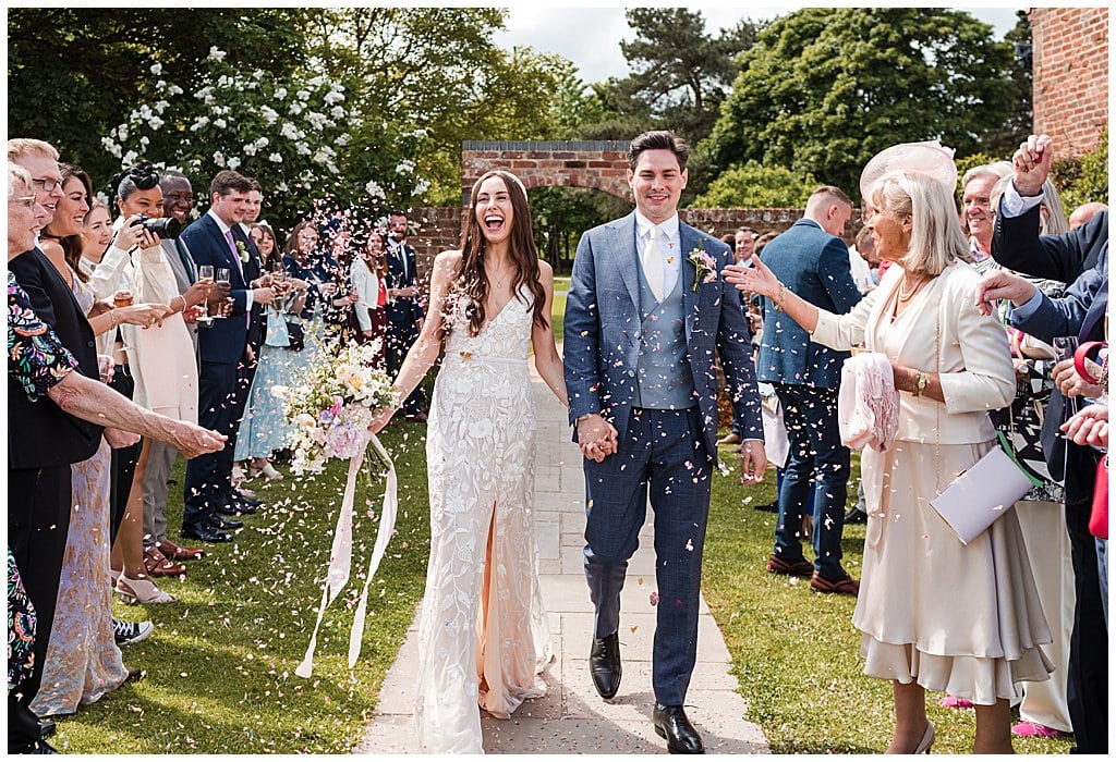 happy couple walk through confetti in the courtyard at Alrewas Hayes