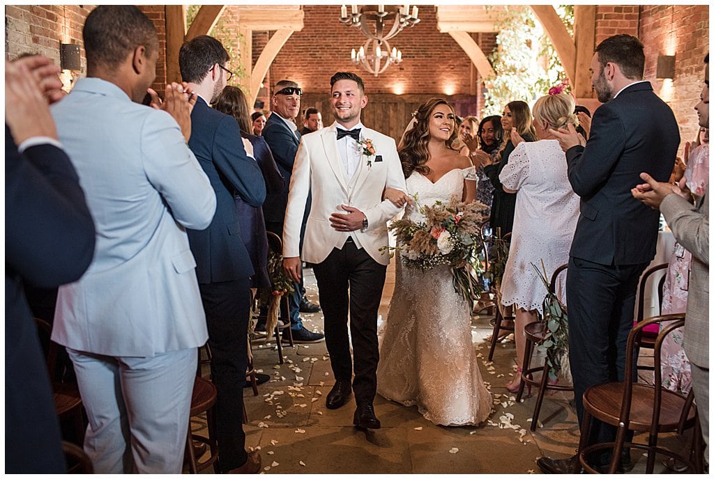 Happy couple walk down the aisle of Shustoke Barn after their wedding ceremony