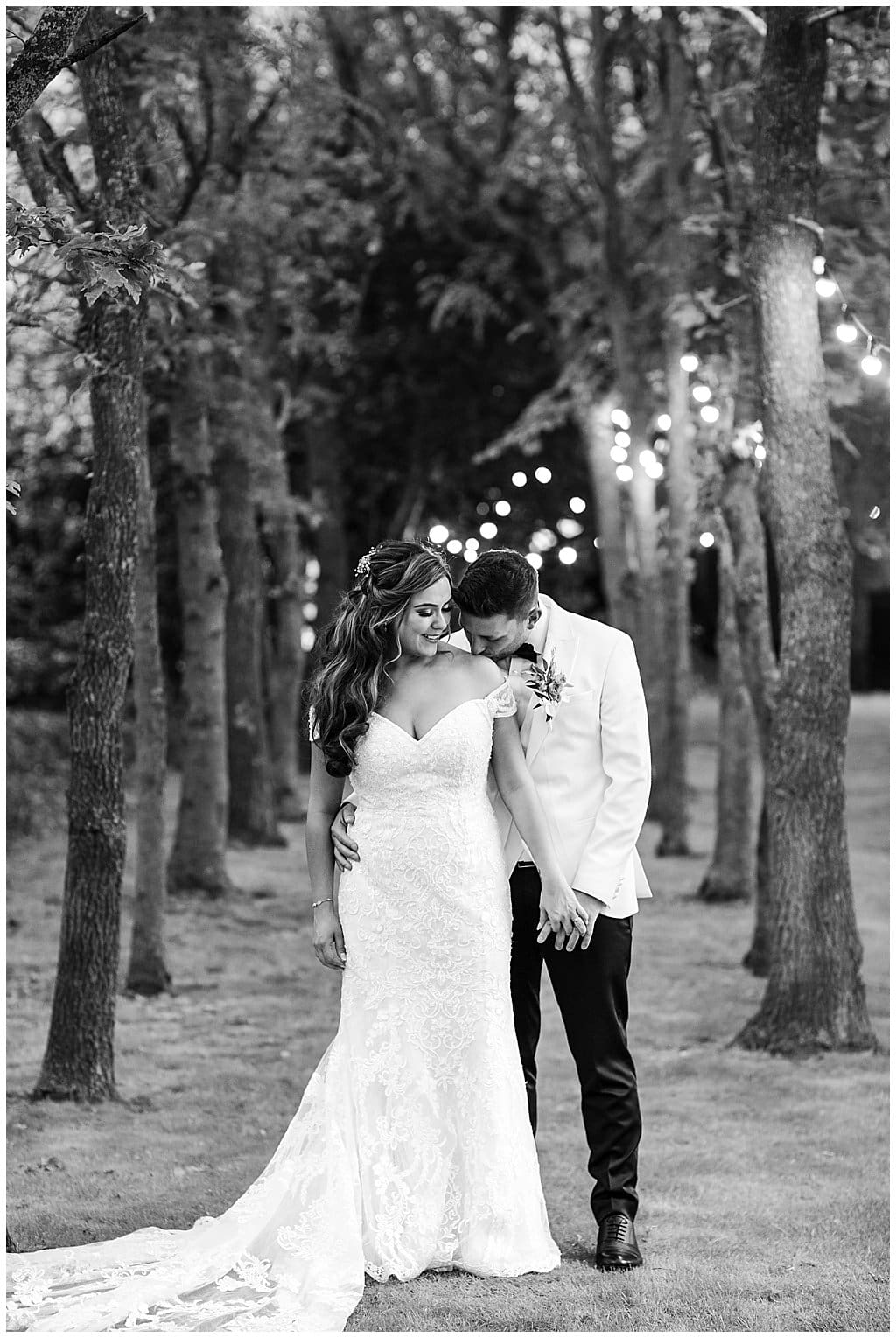 Night time couple portrait at Shustoke Barn. Groom kissing the Bride's shoulder 