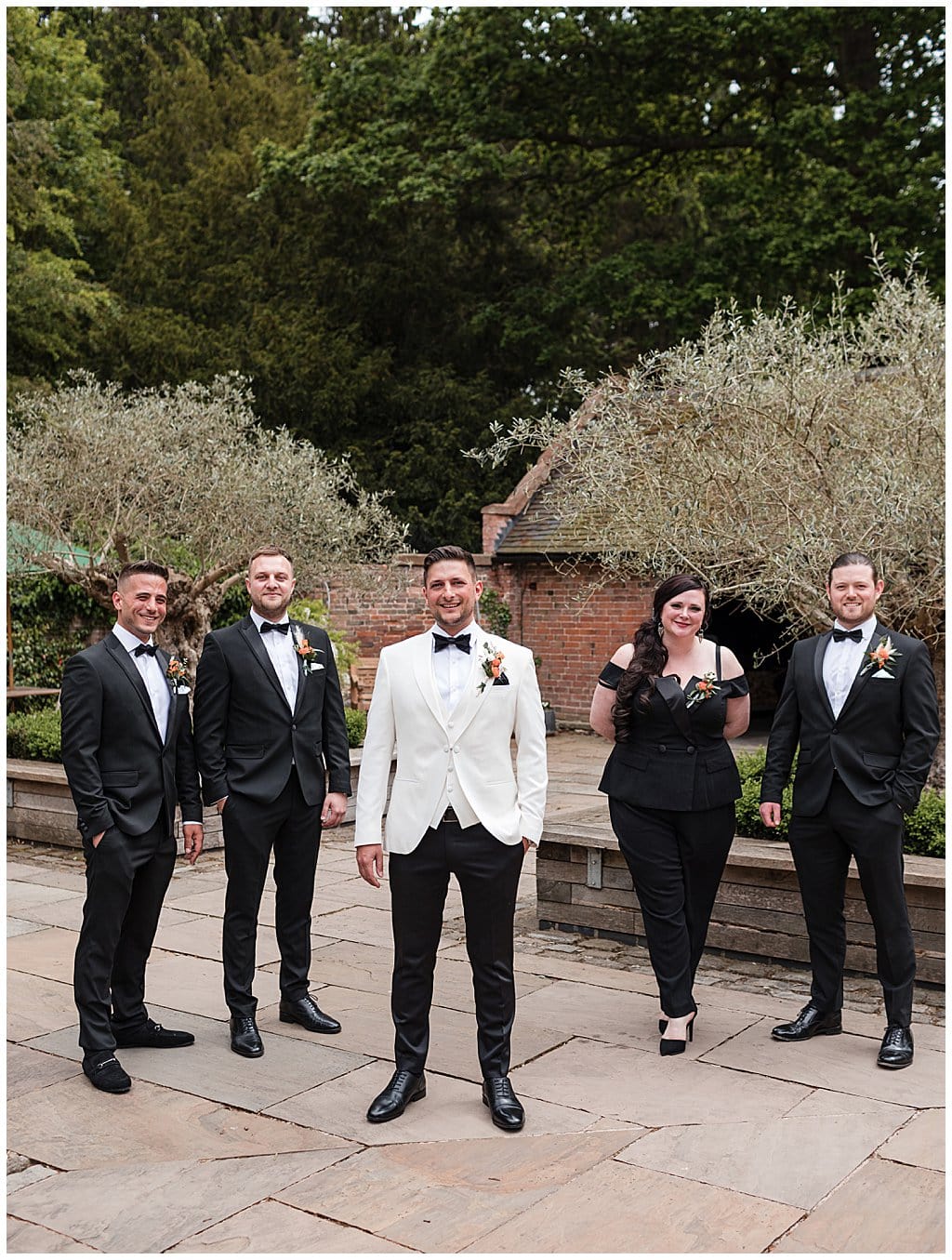 Groom, groomsmen and grooms woman wearing classic black tie tuxedos. Groom wearing white tuxedo