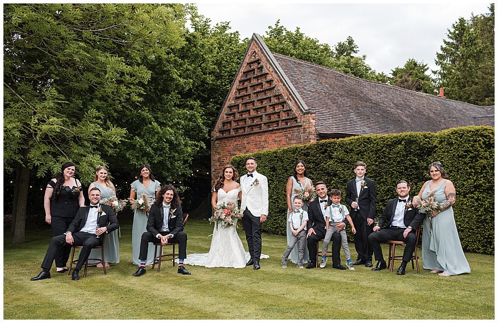 Bridal party group photo at a black tie wedding with pampas grass outside Shustoke Barn