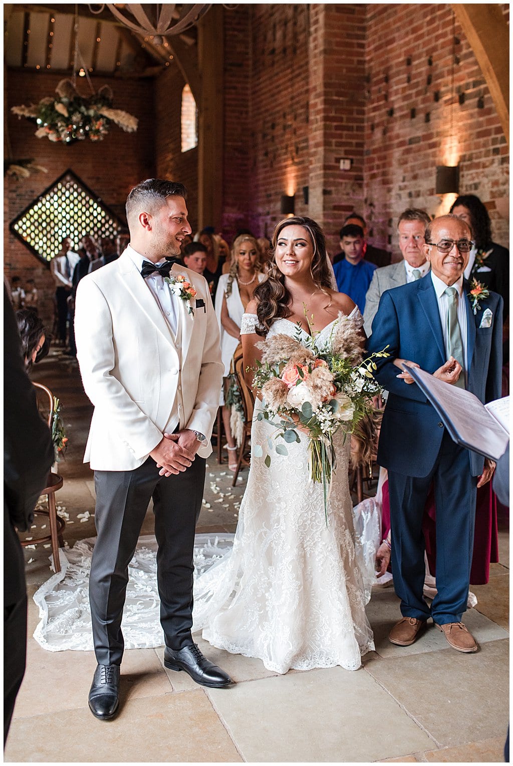 Black tie wedding at Shustoke Barn. Bride holds pampas bouquet and Groom wears a white tuxedo. 