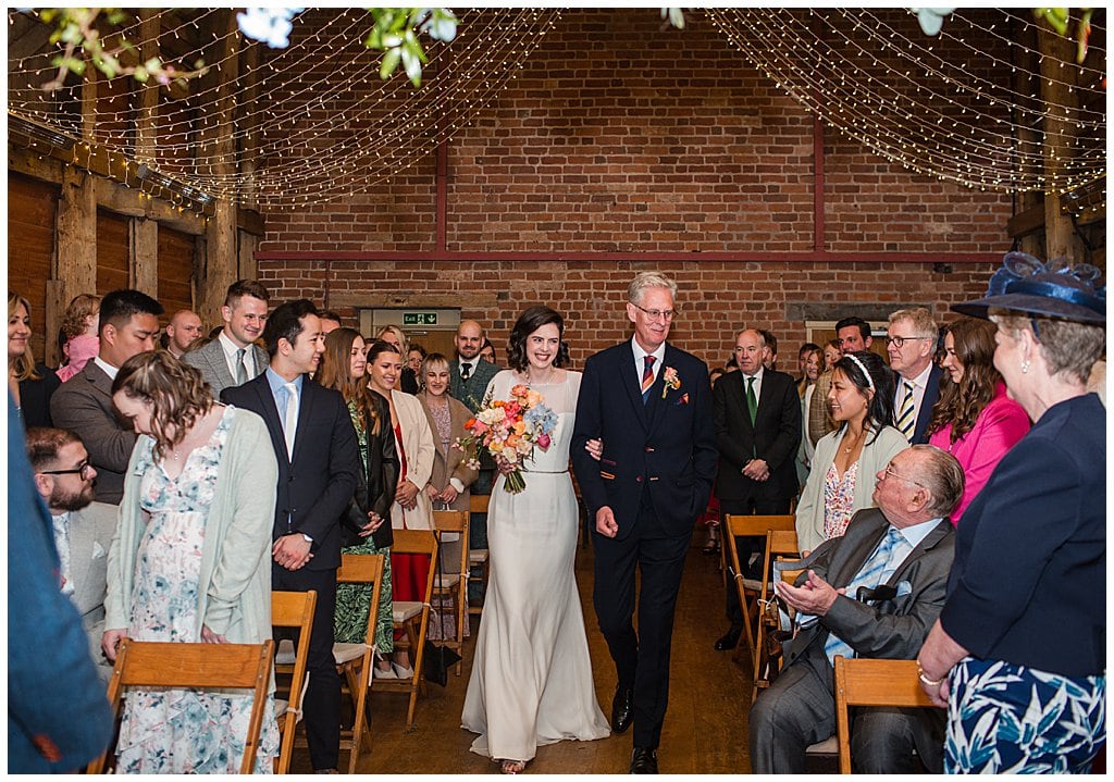 Bride walks down the aisle arm in arm with her Father