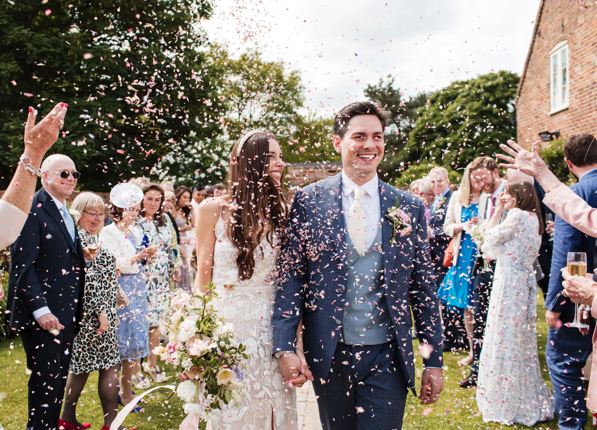 Bride and Groom holding hands walking through confetti