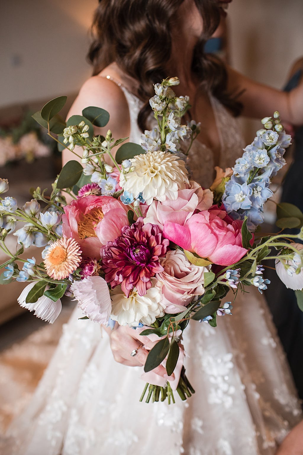 colourful Brides bouquet of coral tree peonies, dahlias and blue delphiniums