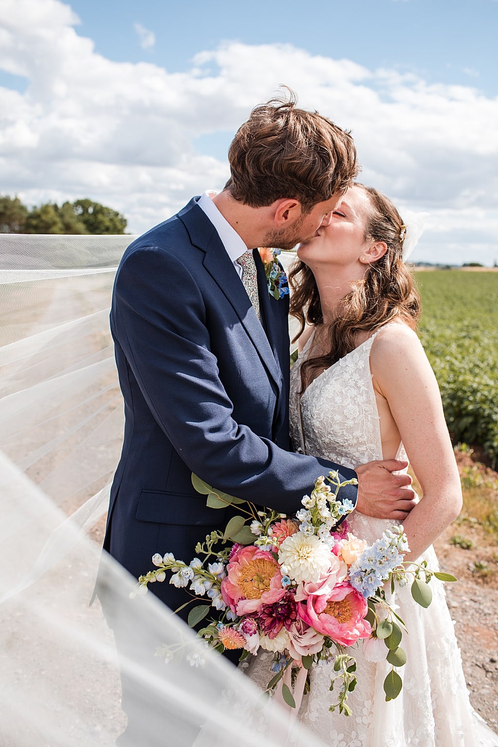 Bride and Groom kissing with wind blowing Brides Veil