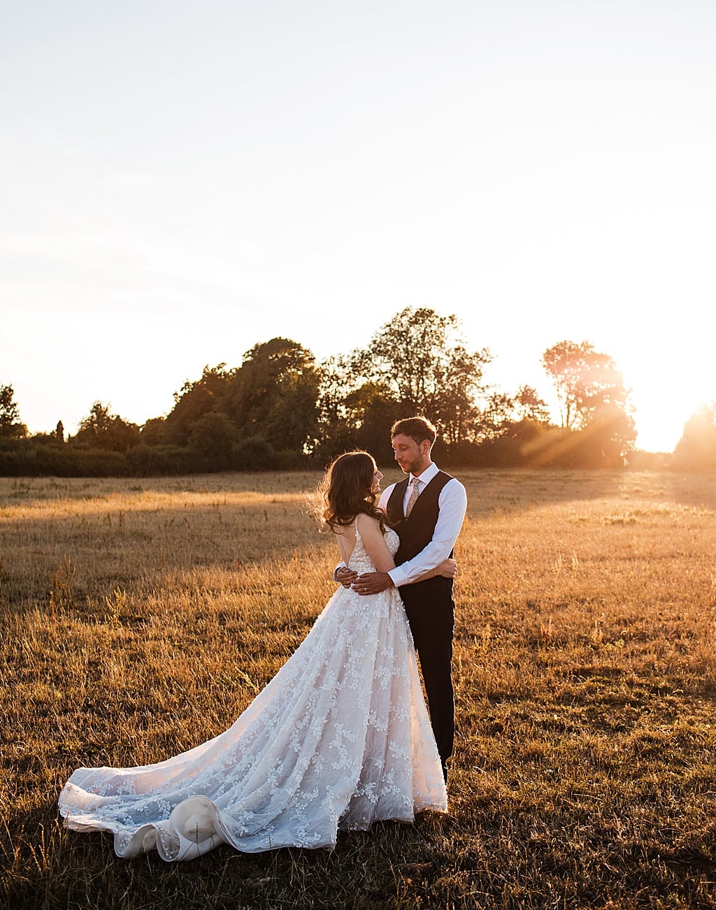 Couple portrait of bride and Groom holding each other in a cornfield at sunset