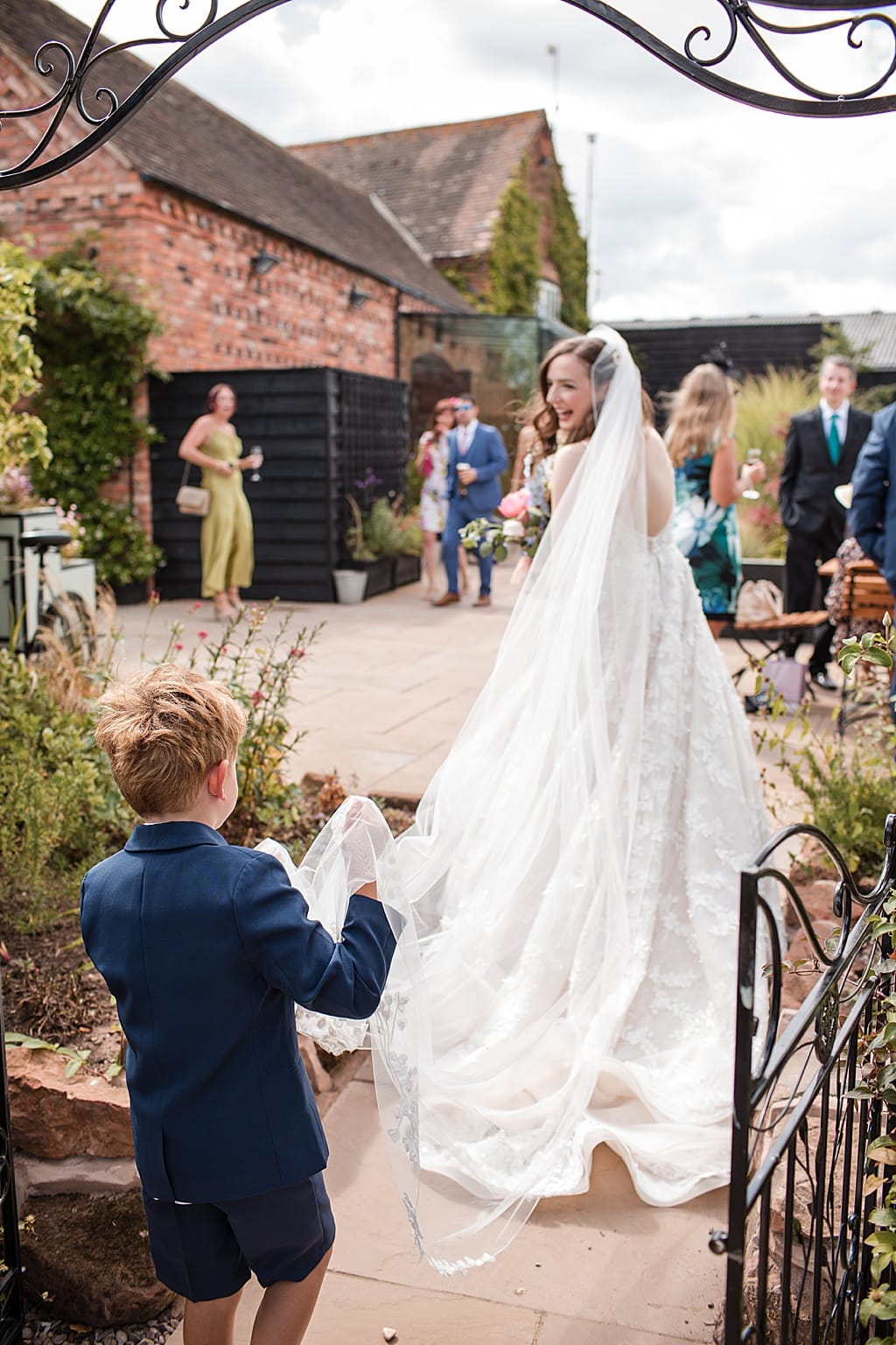 Bride looking back at her young Paige Boy carrying her veil