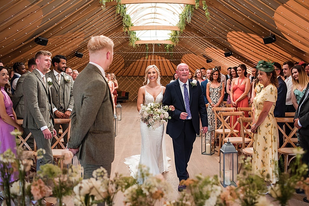 Groom wearing green tweed suit sees Bride for the first time as she walks down the aisle with her Dad