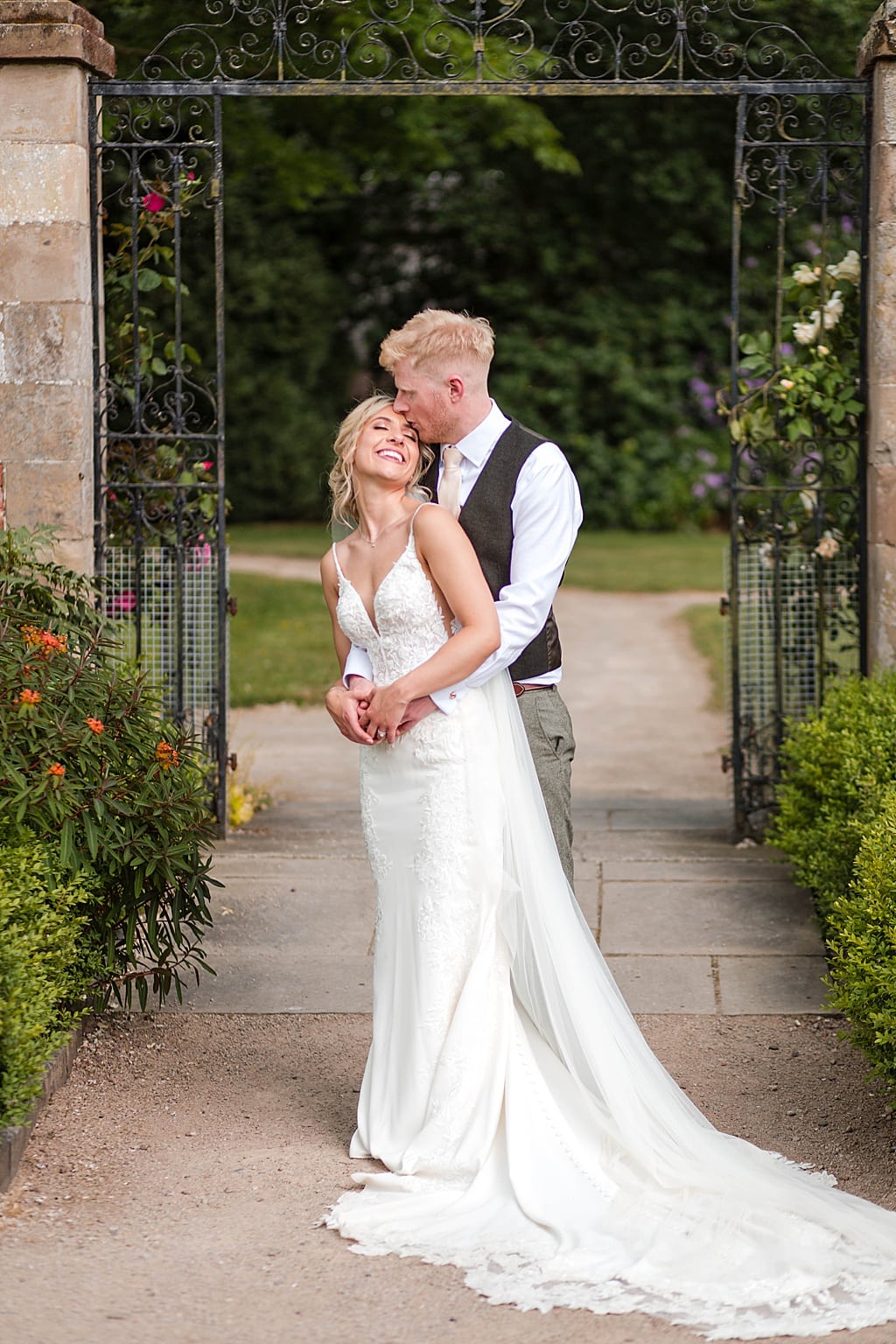 Bride and Groom embrace in front of iron gates at Thorpe Garden