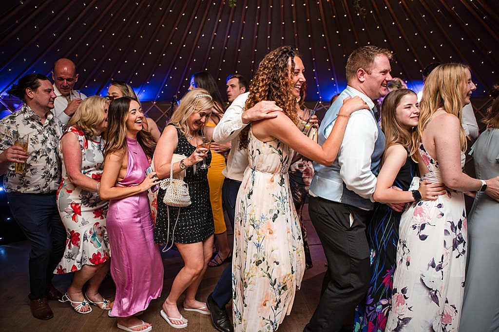 line of guests at a wedding doing the conga at a fun Summer wedding at Thorpe Garden