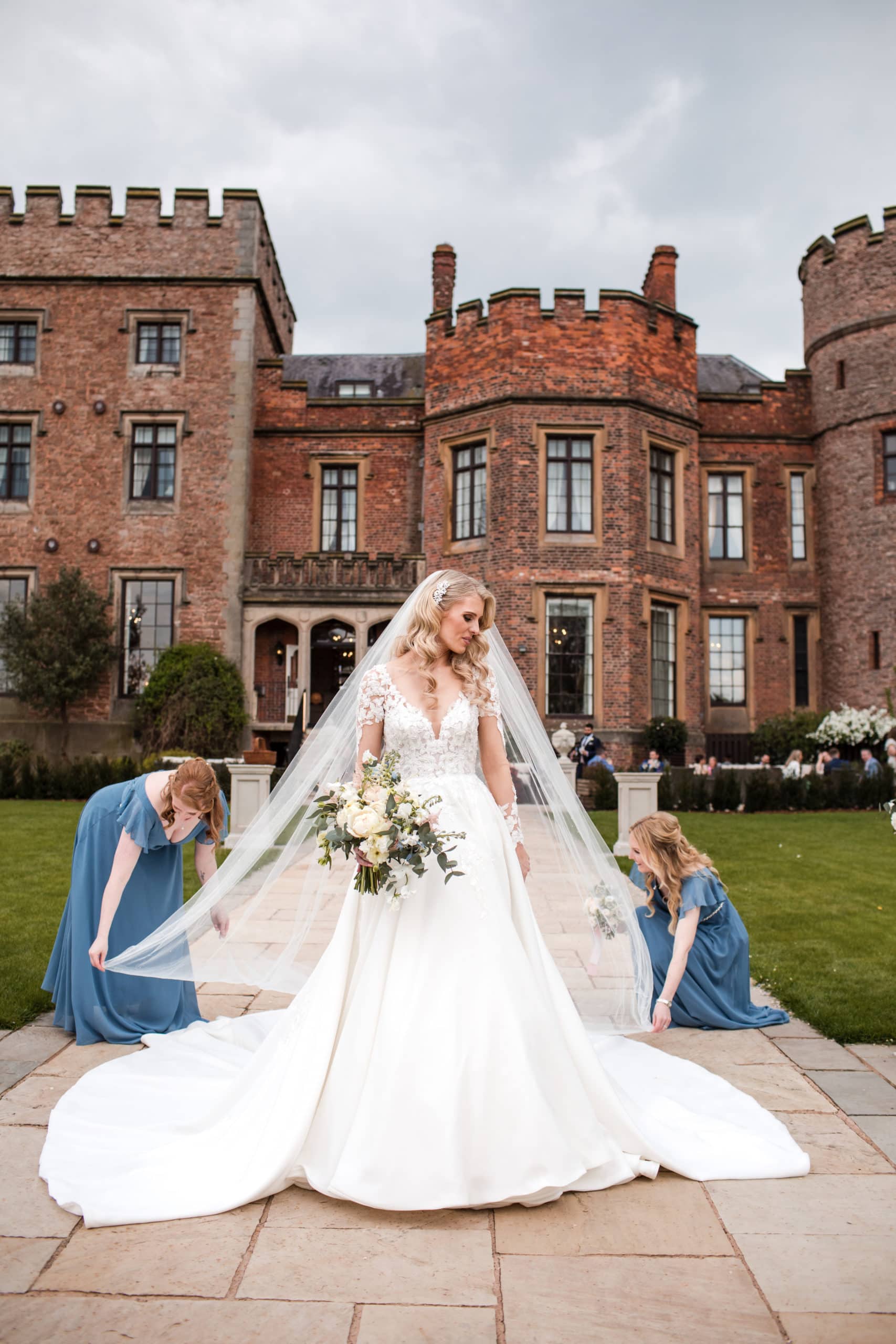 Bridesmaids arrange Brides veil with Rowton Castle in the background