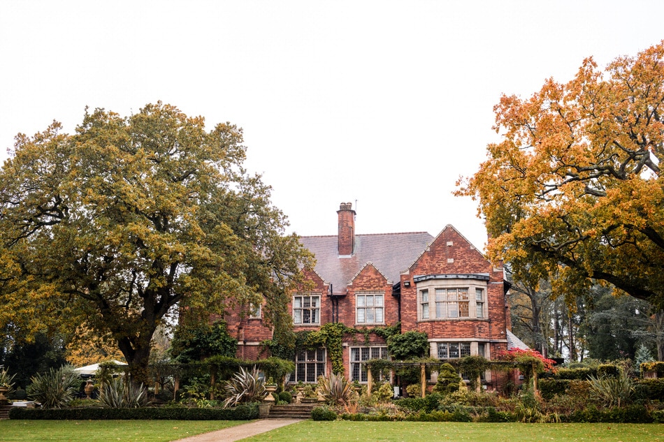 Red Brick luxury mansion house wedding venue, framed by colourful Oak trees in Autumn