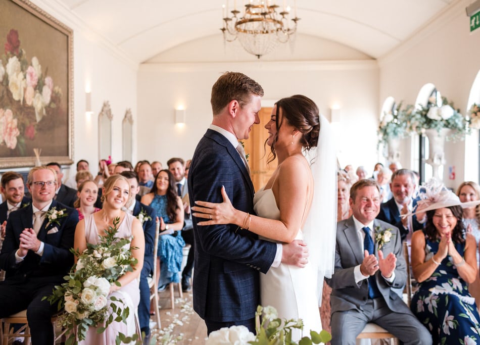 Bride and Groom face each other, looking happy during their ceremony in the Orangery at Alrewas Hayes
