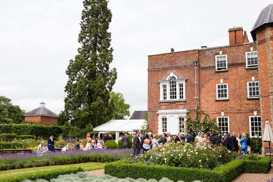 Wedding guests chatting and enjoying the gardens planted with lavender and roses at a Summer wedding reception at Iscoyd Park