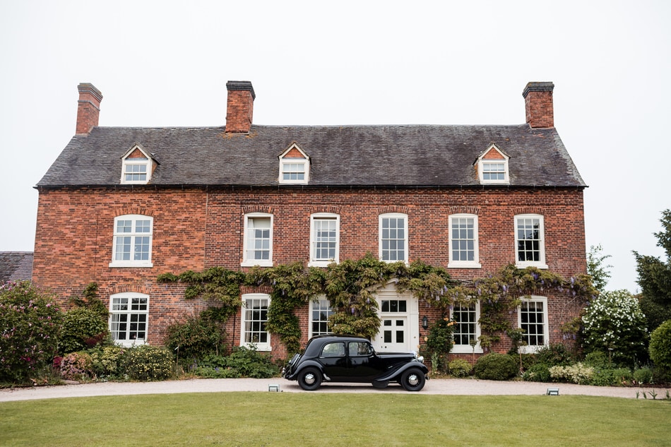 The front view of a Georgian country house wedding venue in West Midlands. A black vintage car parked in front