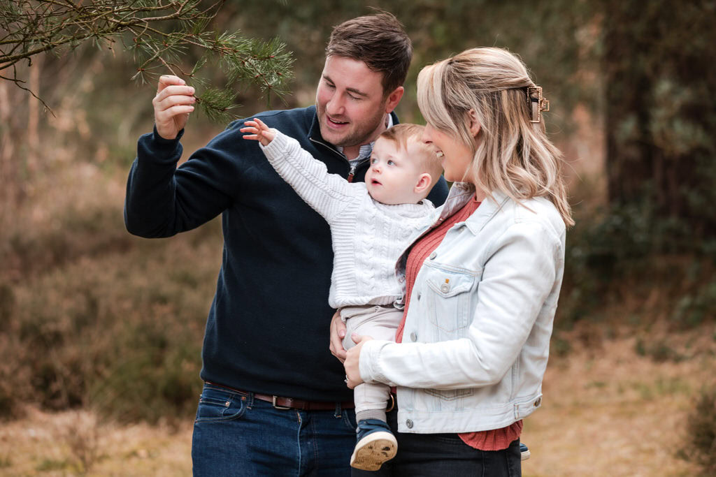 young parents hold their toddler and look at nature in Sutton Park