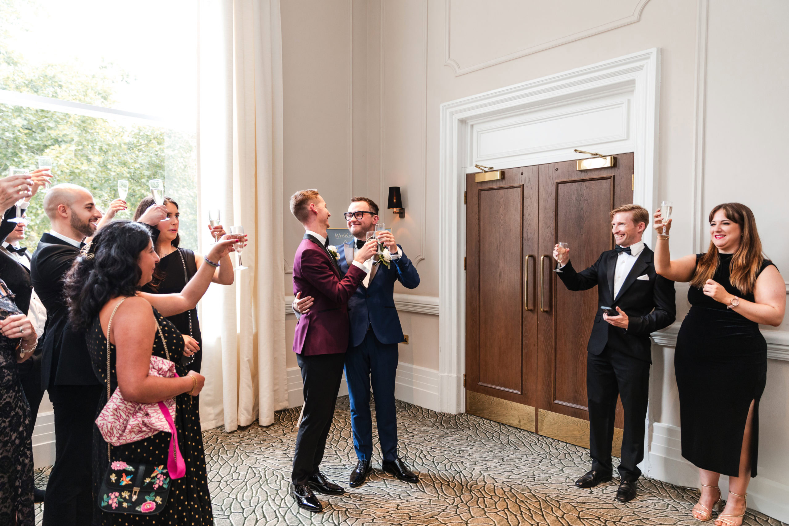 Candid photo of guests toasting two Grooms at their intimate wedding at The Grand Hotel in Birmingham