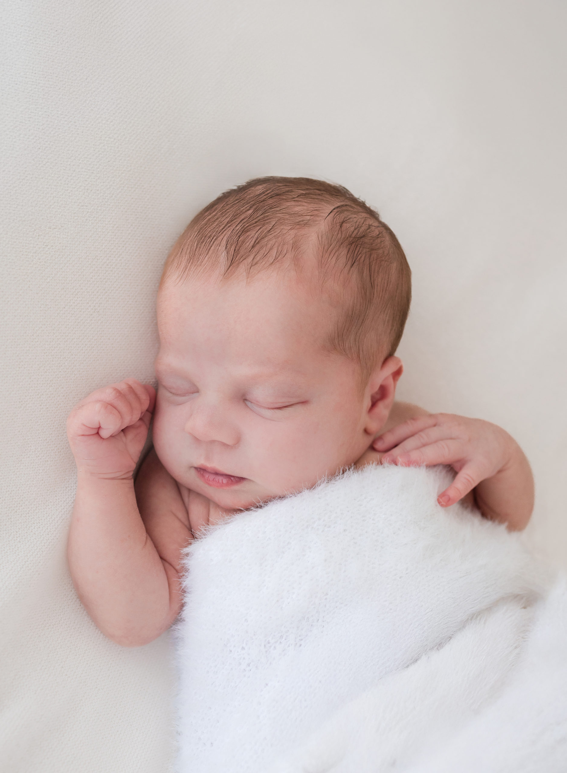 baby wrapped in a white fluffy blanket, sleeping during a natural newborn photography session in Birmingham