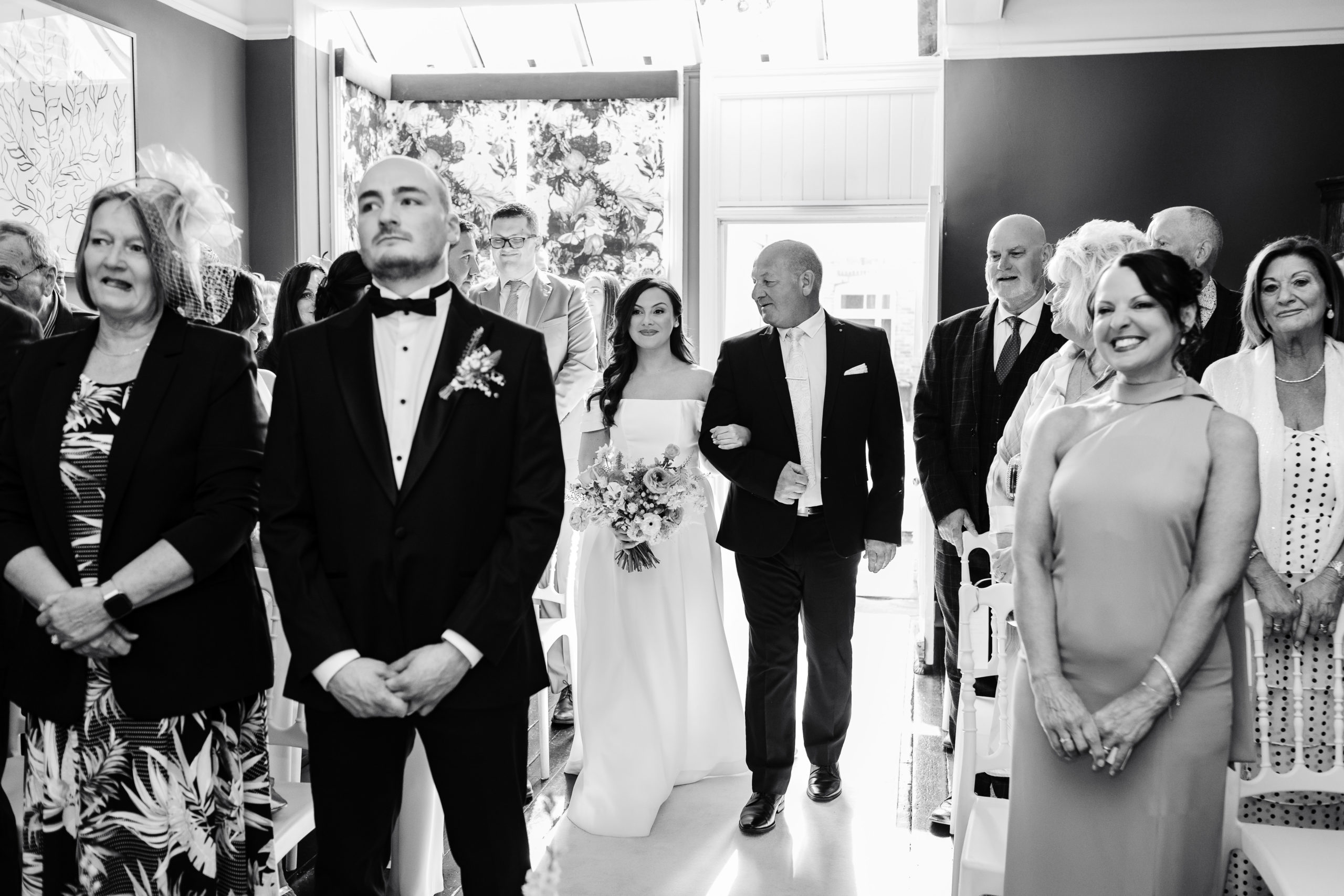 Bride walking into the ceremony room holding Dad's arm at St Johns House Lichfield