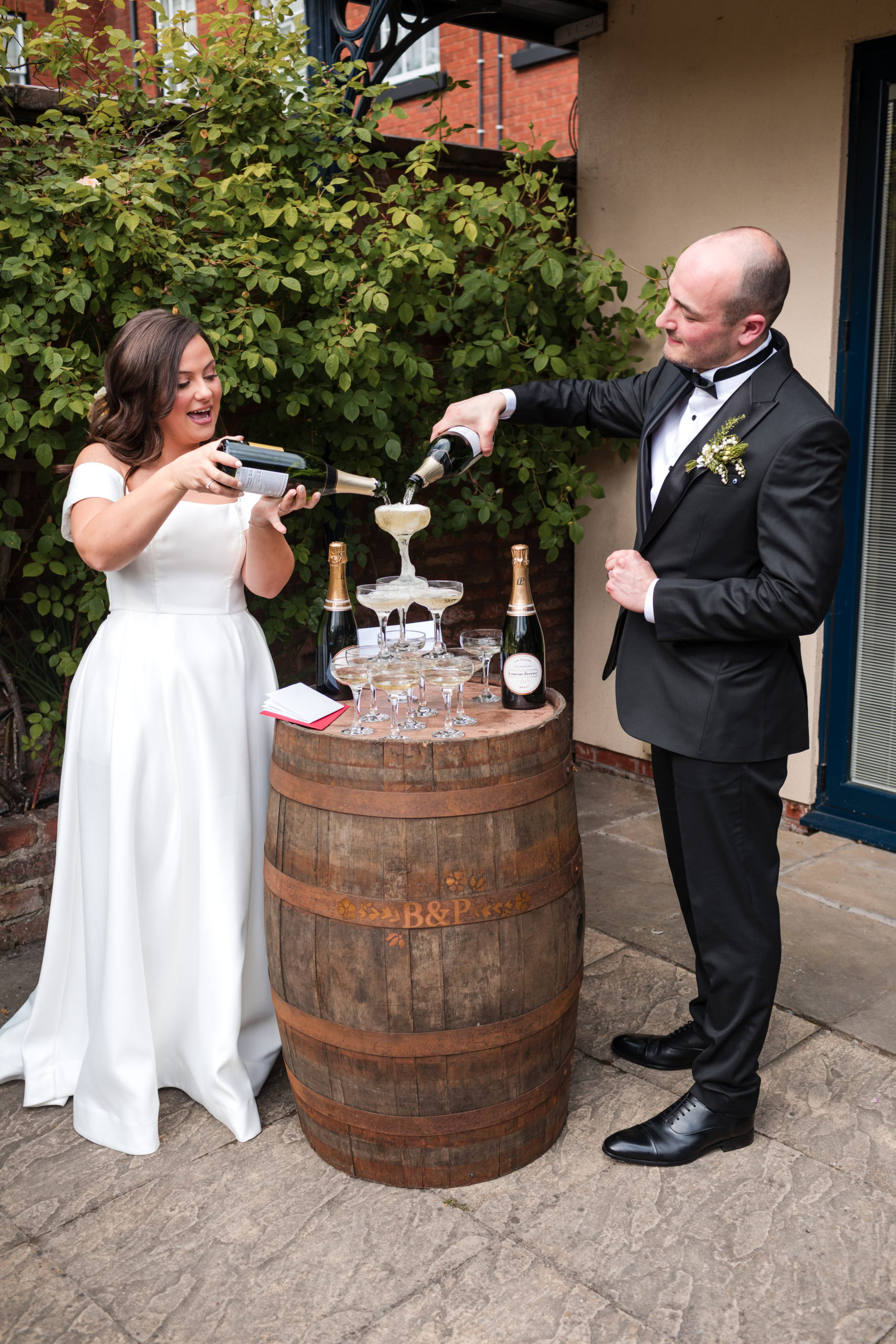 couple pour champagne into a champagne tower at during their wedding reception at St Johns House