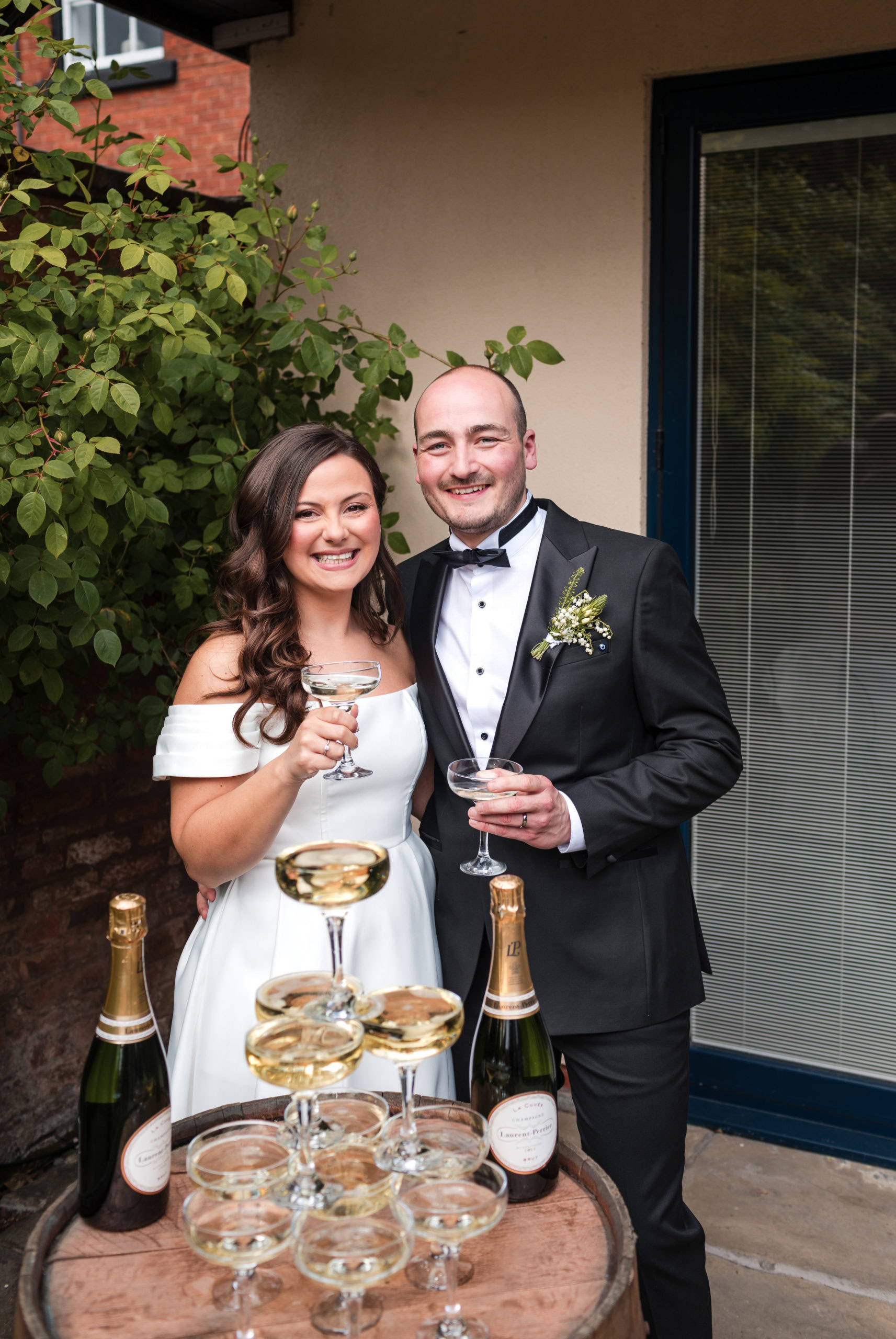 Natural happy portrait of a newly married couple standing with a champagne tower