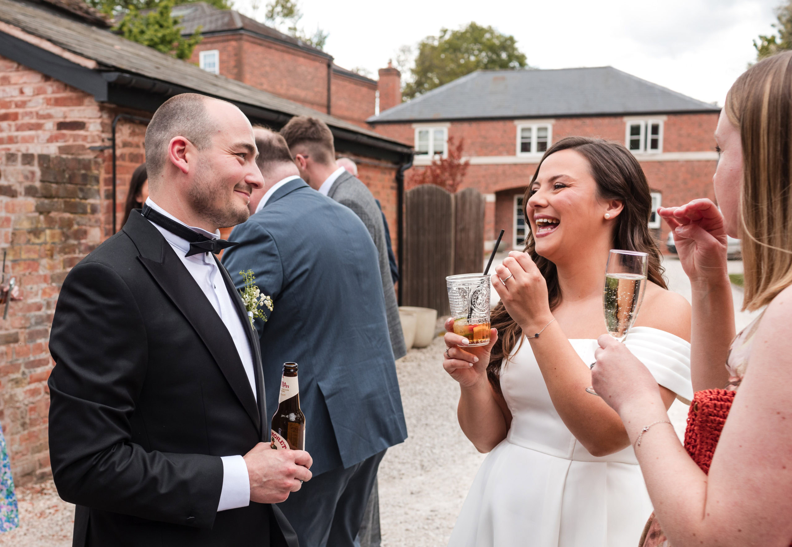 candid moment of a Bride and Groom laughing with drinks at their drinks reception
